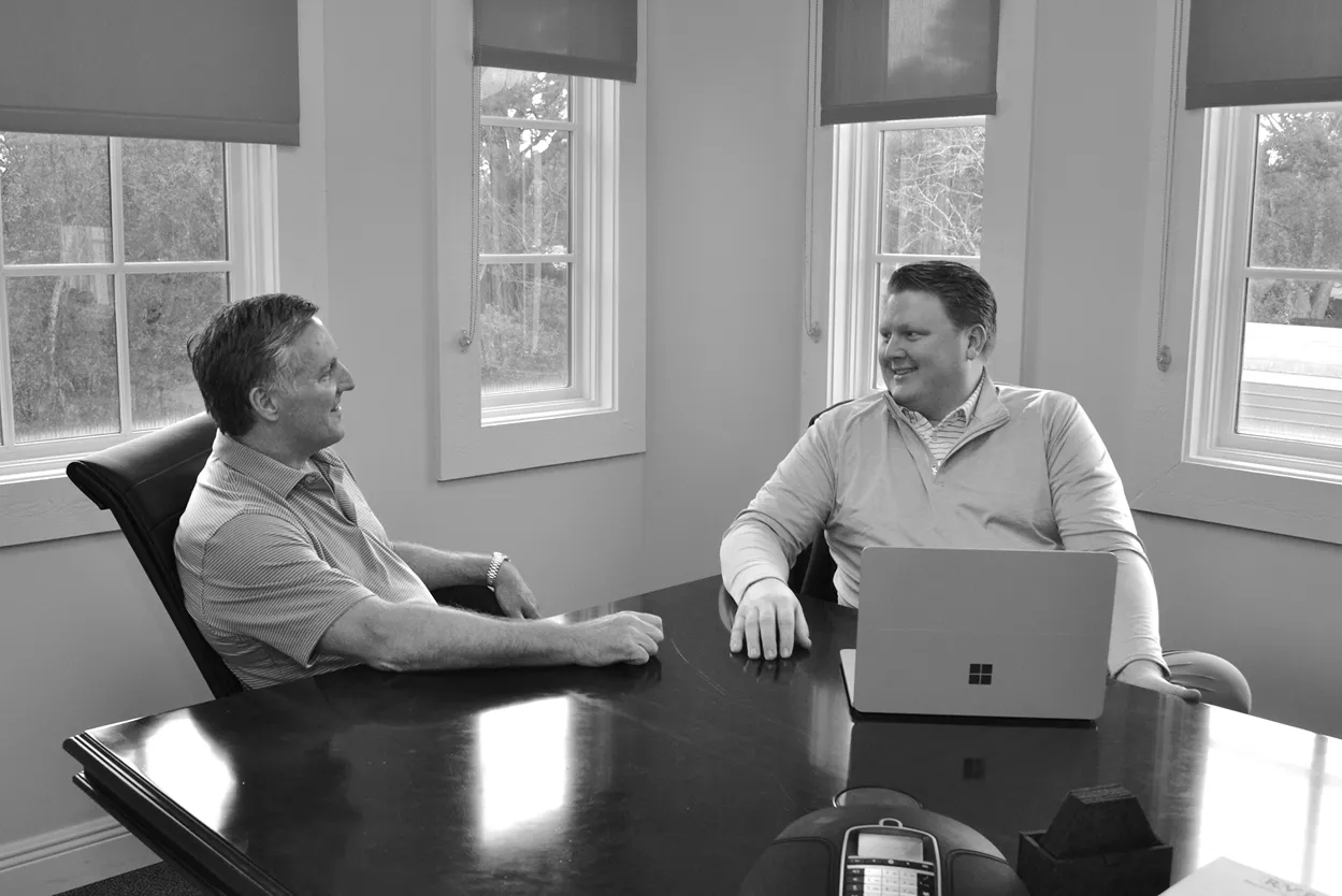 Black and white photo of two men sitting at a conference table in a business meeting