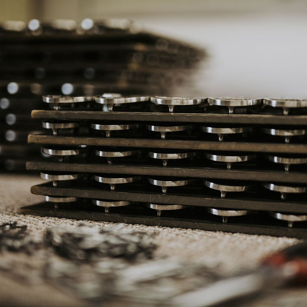 Stacked trays of pewter components during manufacturing, representing large-scale production and coordinated recognition rollouts.