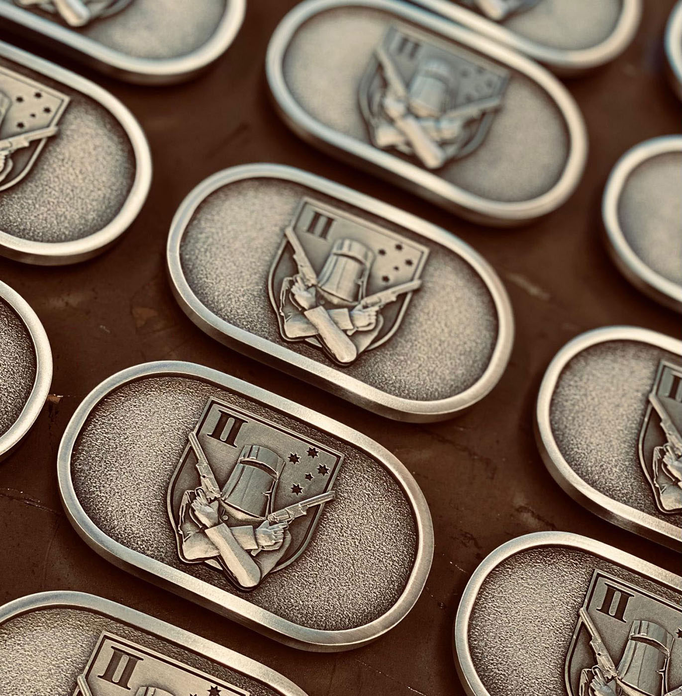 Custom pewter military inspired belt buckles in production with raised emblem detailing