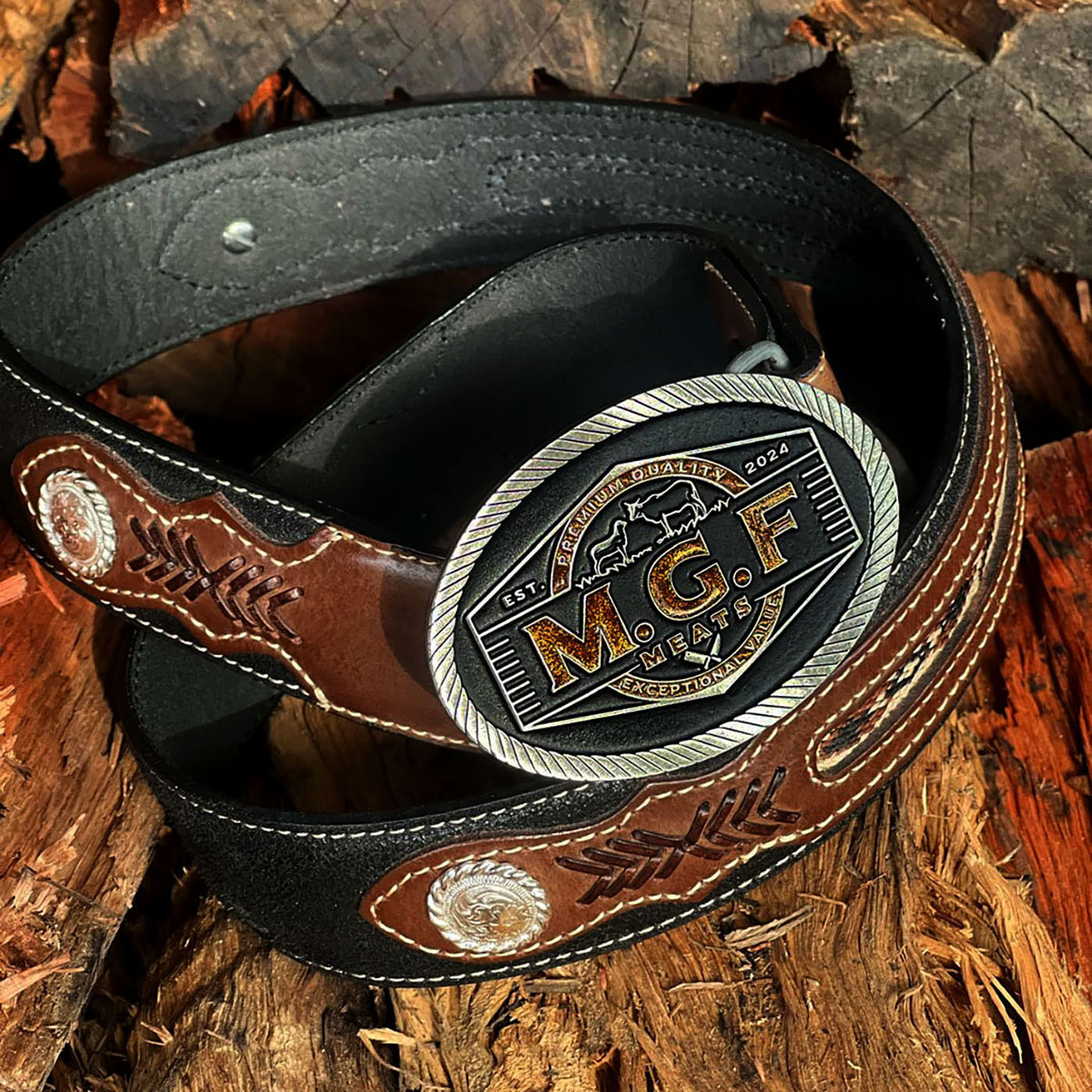 Custom western style MGF Meats belt buckle photographed on hand tooled leather belt