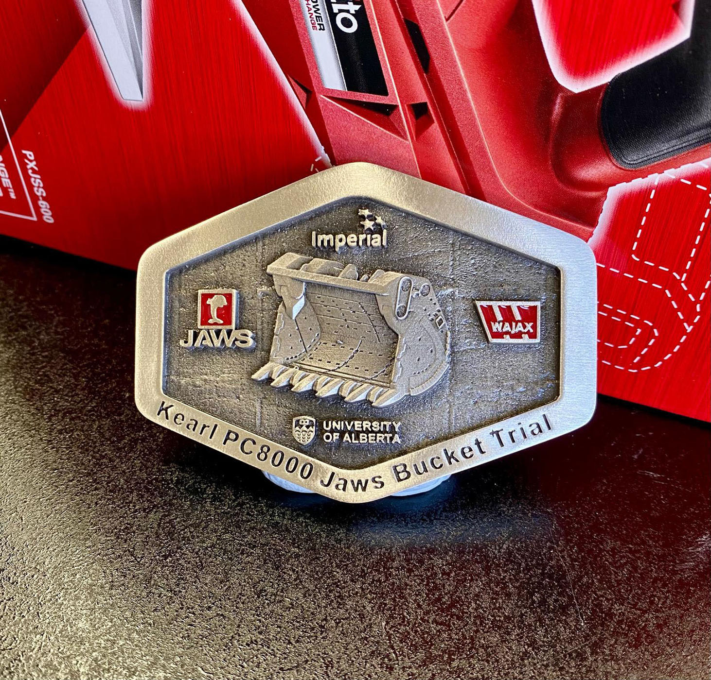 Custom mining belt buckle recognising the collaborative bucket project partners involved in the Jaws bucket trial