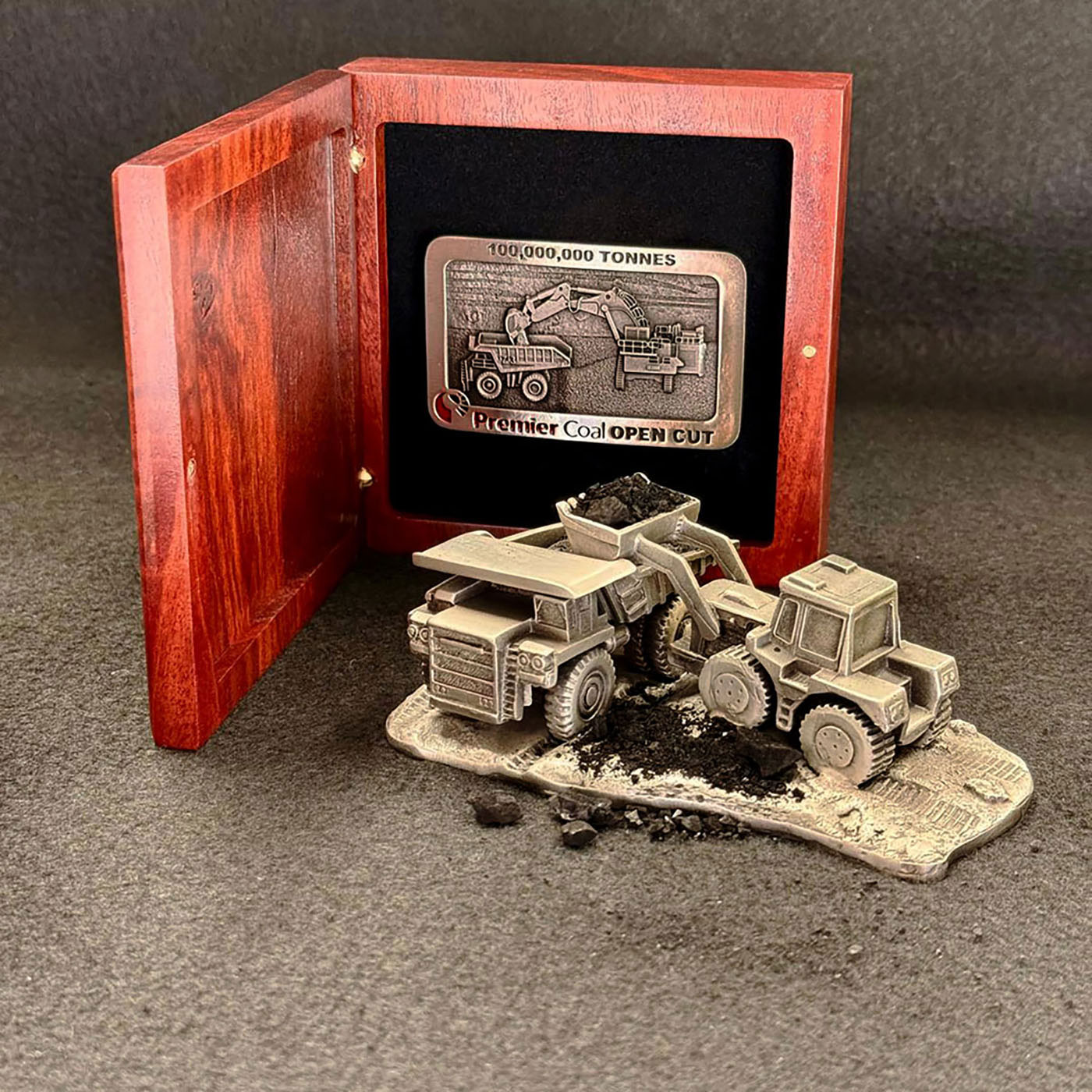 Custom pewter mining presentation piece featuring haul truck and loader models with commemorative buckle display, manufactured in Western Australia by Buckingham Pewterbackground image]
