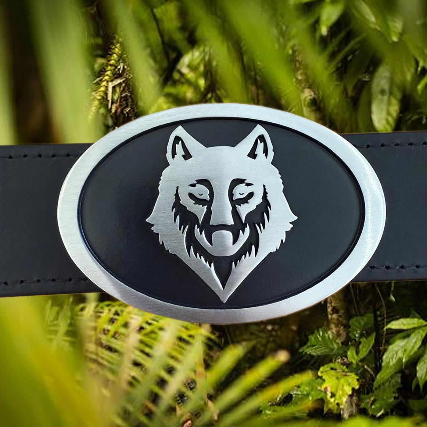 Black wolf motif custom belt buckle photographed in outdoor natural setting