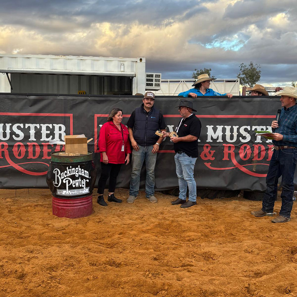 People gathered at the Mullewa Muster & Rodeo event beside a Buckingham Pewter display barrel during an outdoor award presentation in Western Australia.