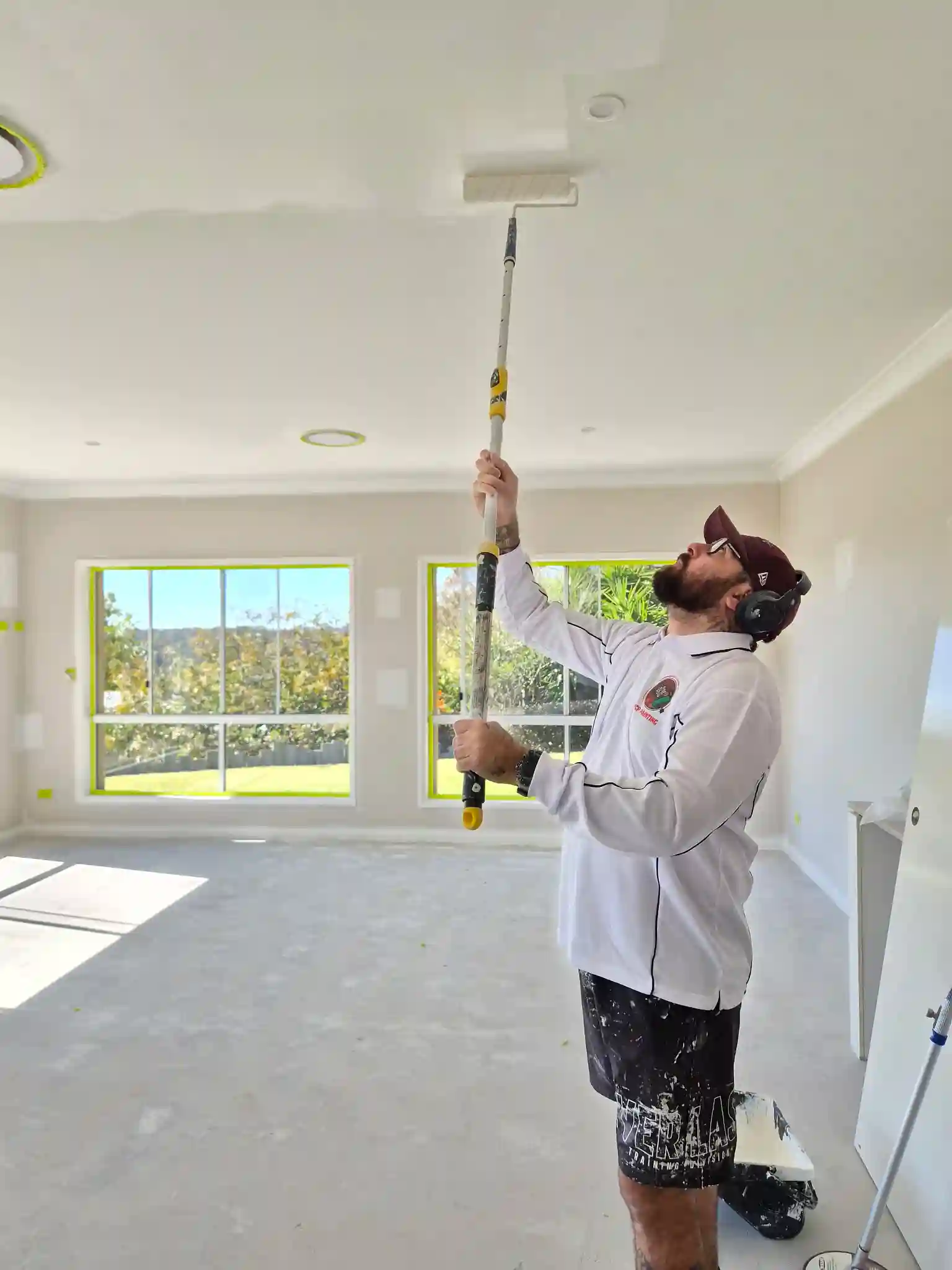 Owner of MCP Painting, Massey, painting a roof with a headset on
