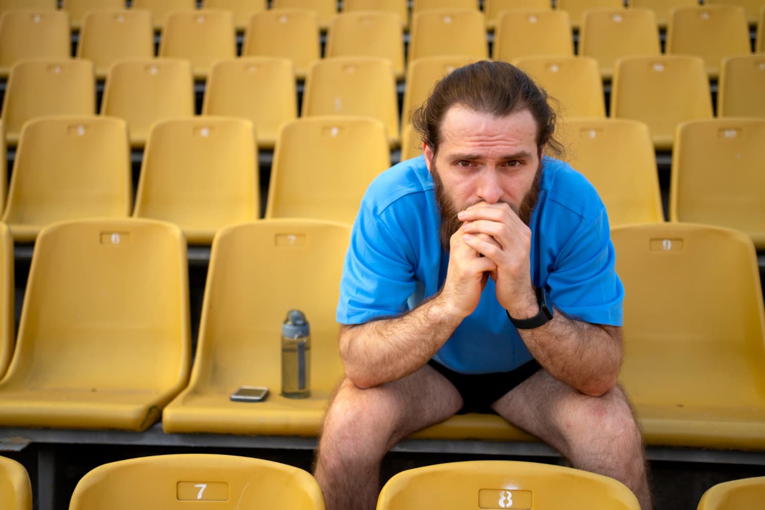 Man pondering his situation sitting down in a stadium