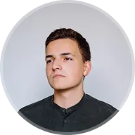 Portrait of a young man with short dark hair wearing a black shirt against a plain background.
