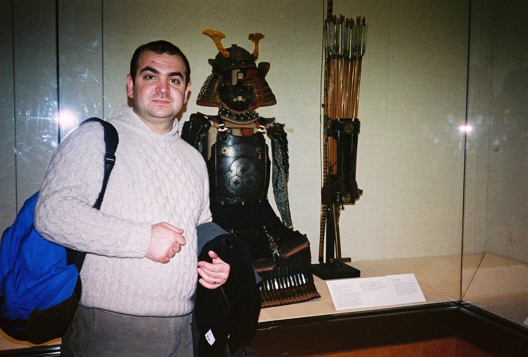 Ahmet Can Yeşildağ beside a cased suit of samurai armor with helmet and arrows, museum photograph, Japan, 2005