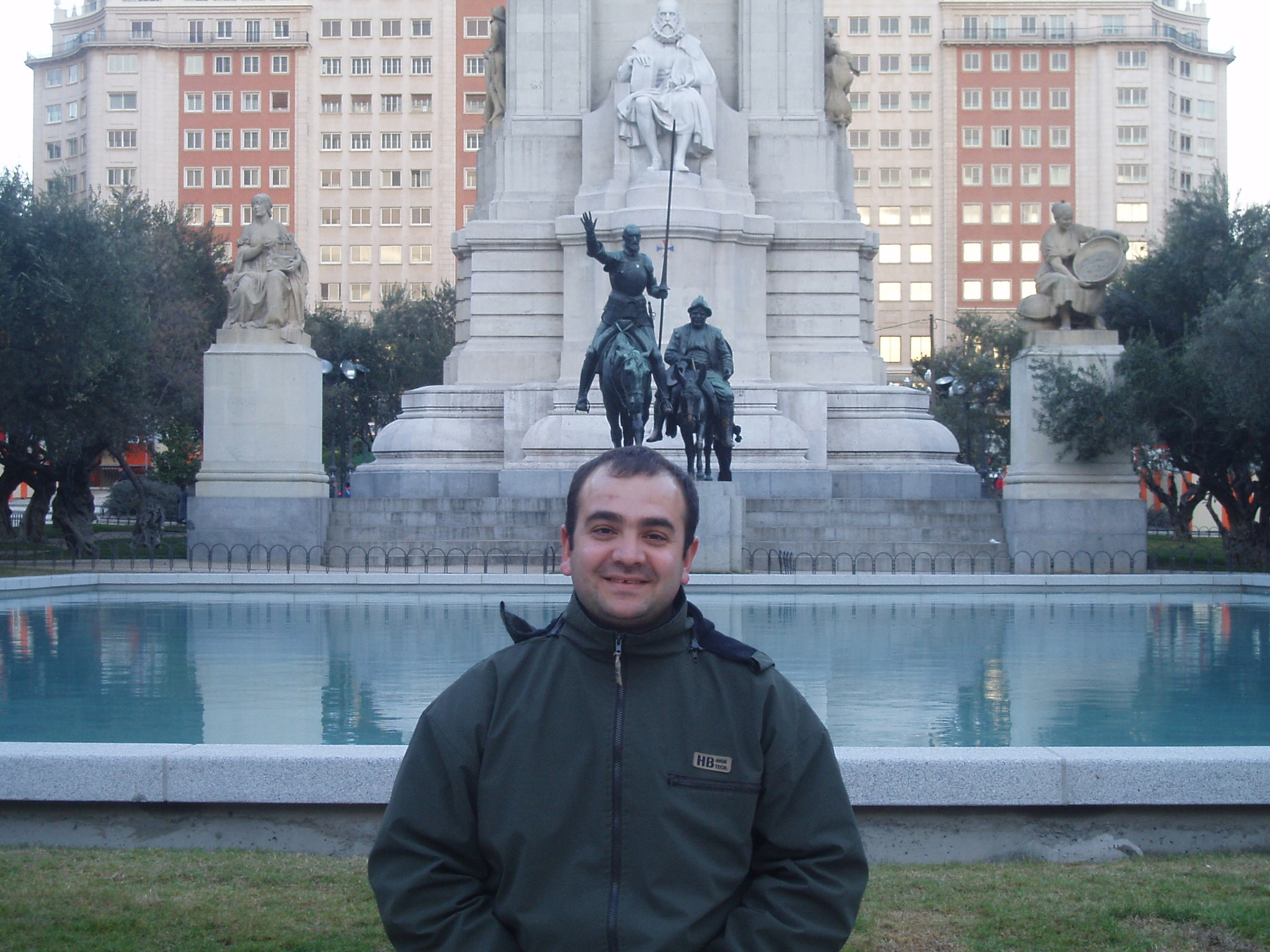 Ahmet Can Yeşildağ at the Cervantes monument in Plaza de España, Madrid, winter 2005 — bronze Don Quixote and Sancho Panza riding ahead of the stone Cervantes