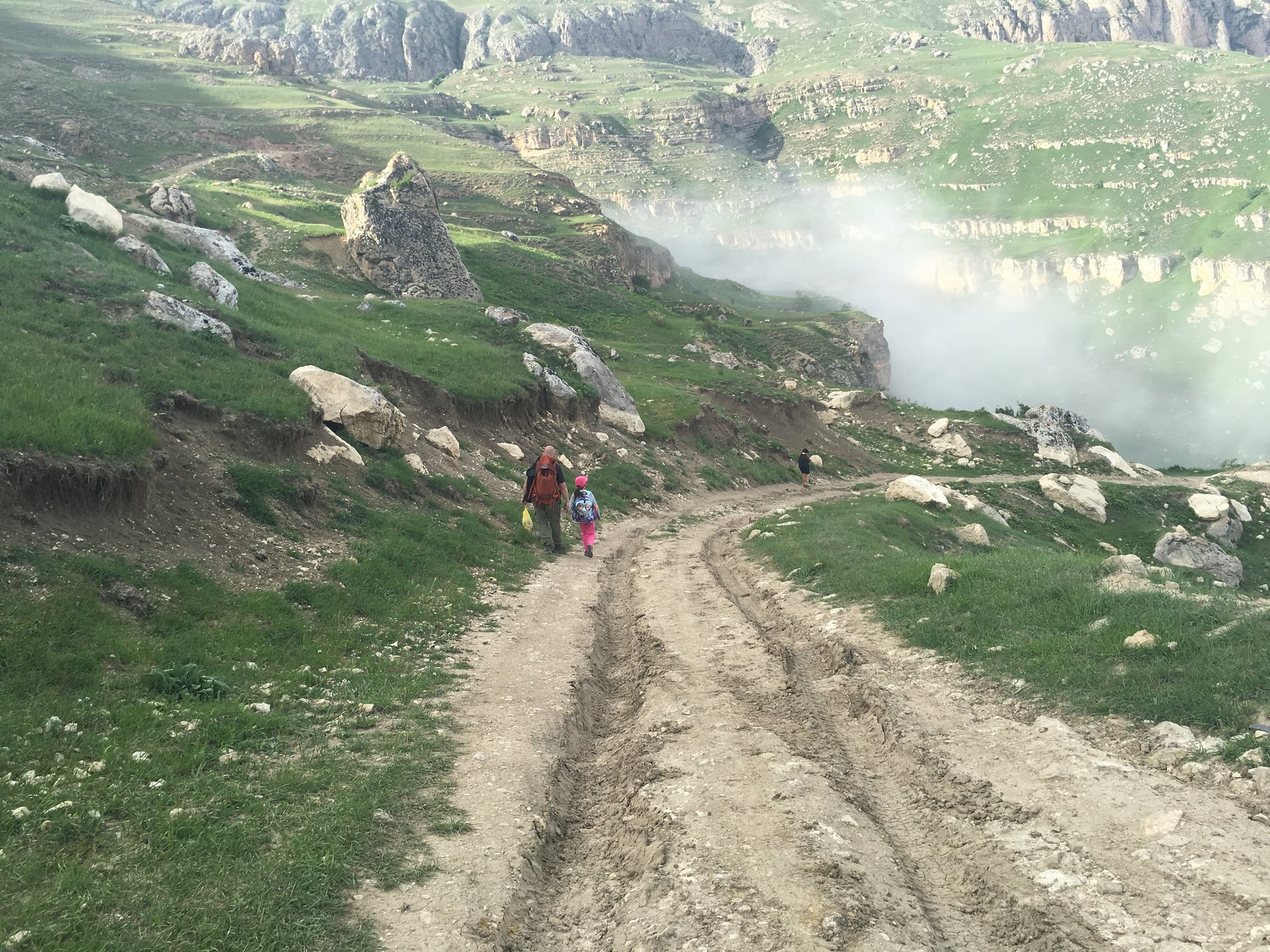 Above Laza, Qusar — a misty mountain track in the Azerbaijani Greater Caucasus, two walkers heading up.