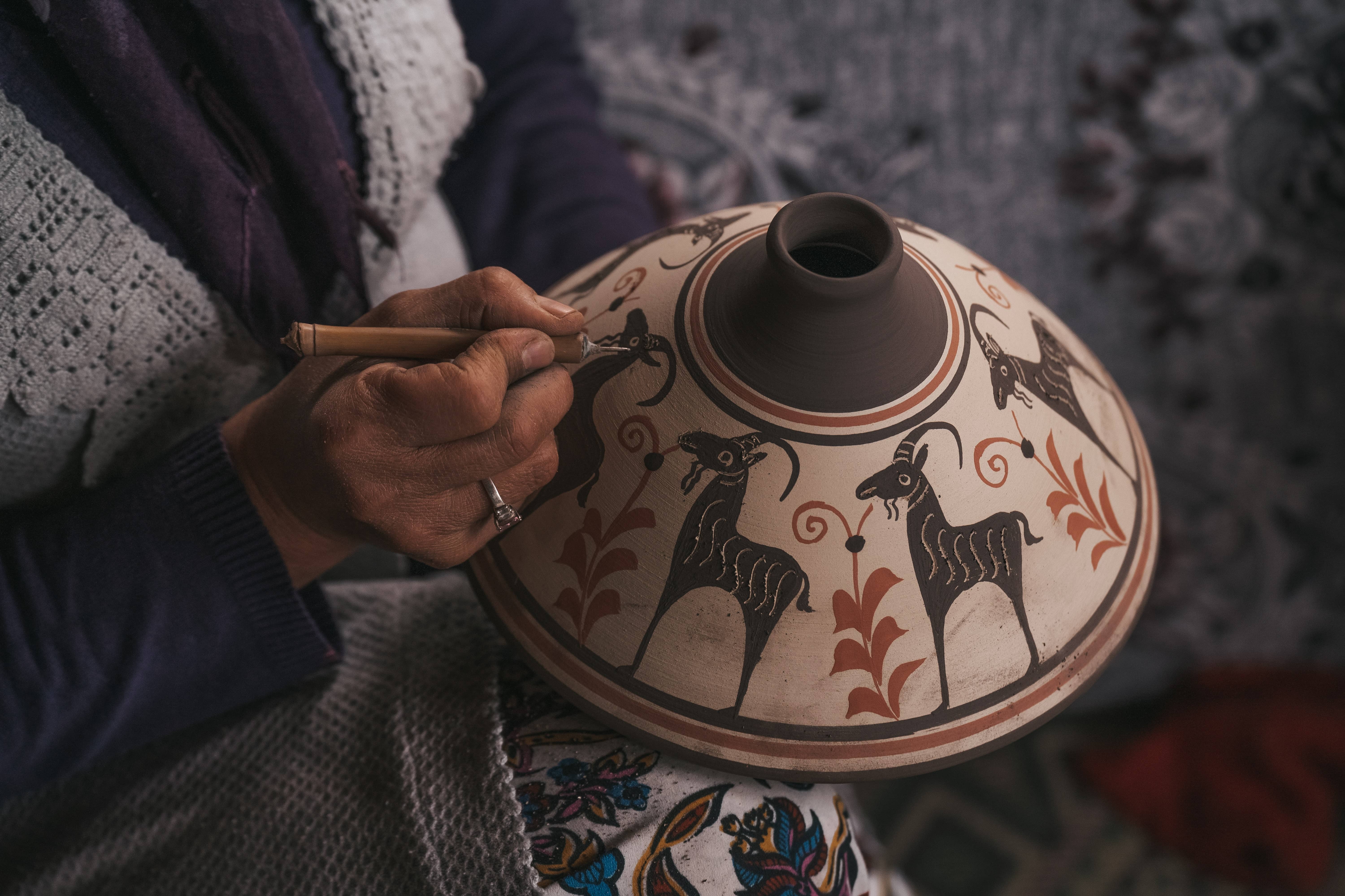 A Denizli artisan painting Anatolian motifs on terracotta