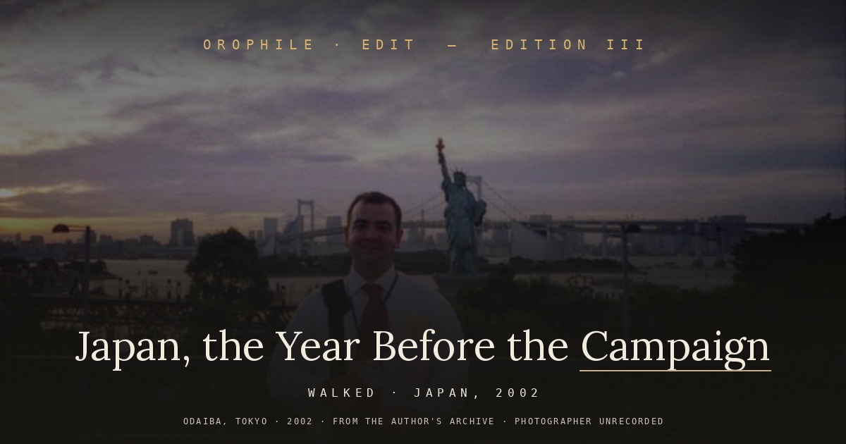 Edition III — Japan, the Year Before the Campaign. The editor at Odaiba, Tokyo, in 2002, with the Rainbow Bridge and the Statue of Liberty replica behind. From the author's archive; photographer unrecorded.