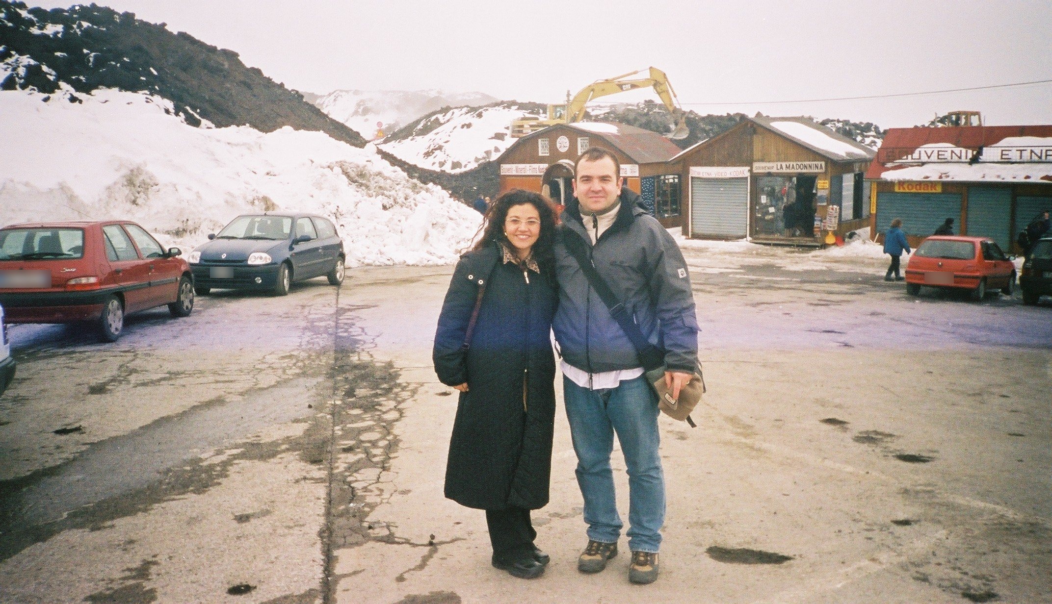 Souvenir huts on Etna in winter 2002, open beside fresh lava and snow, with a digger working behind them