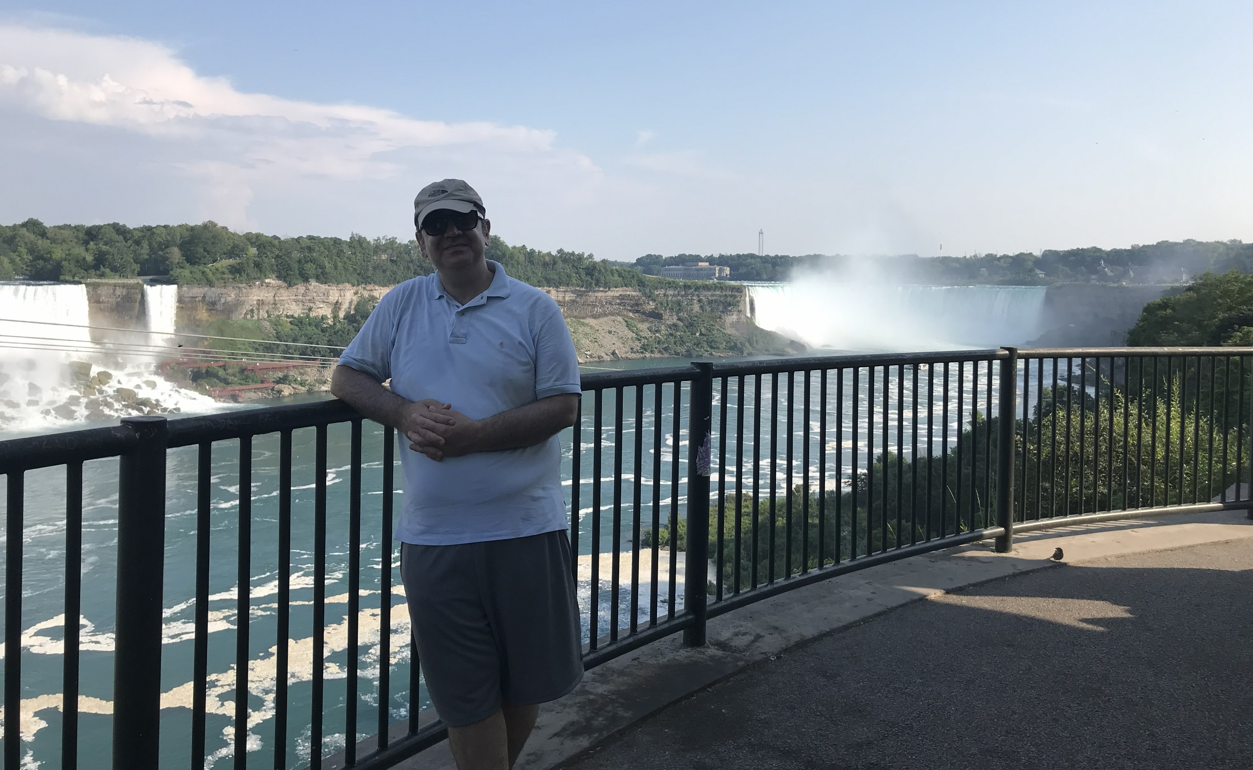 Ahmet Can Yeşildağ at the railing above the Niagara gorge, with the American and Horseshoe Falls behind, July 2020