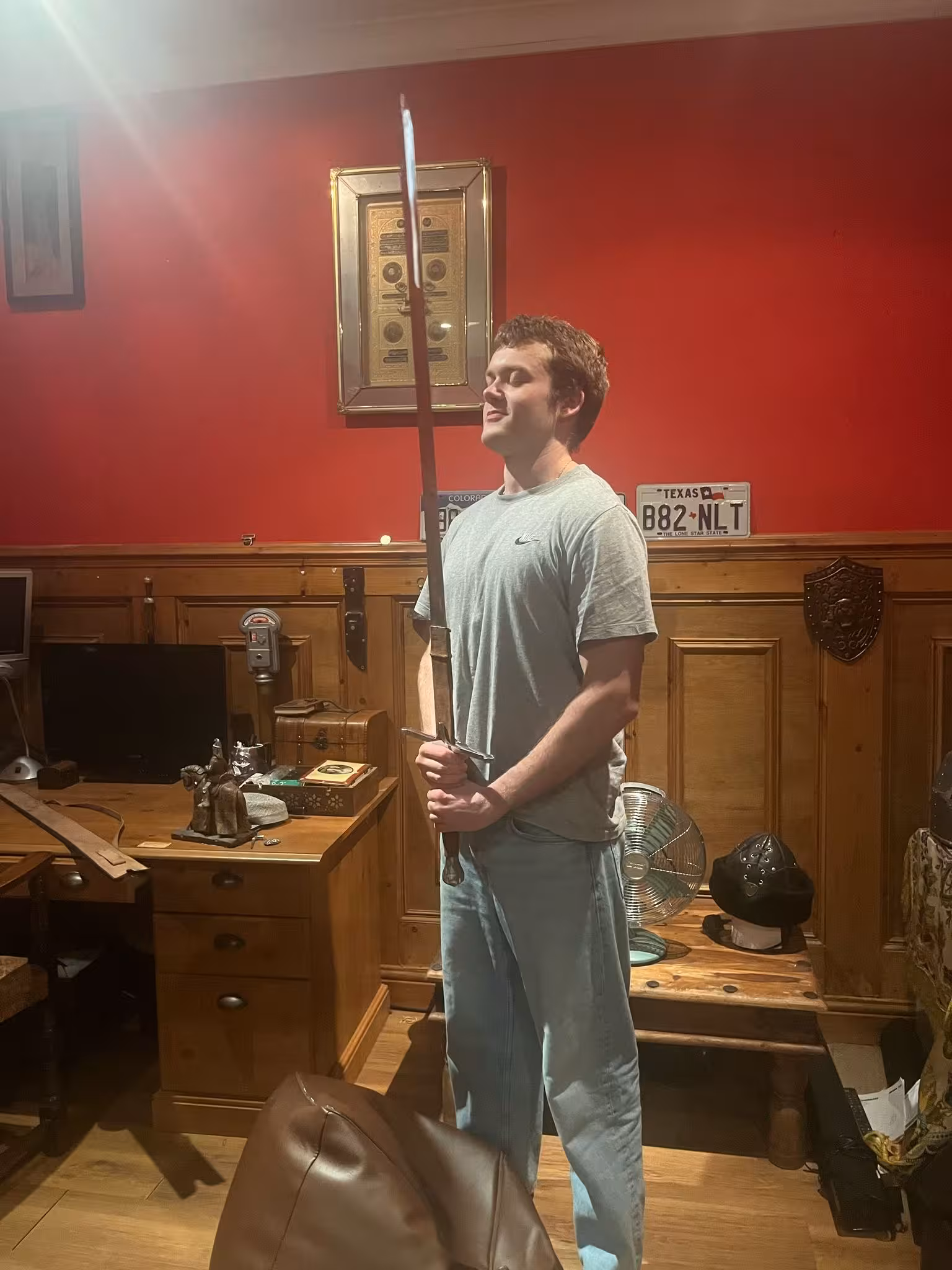 A picture of Oliver Taylor with a sword that he is holding infront of him and pointing it upwards along his chest.