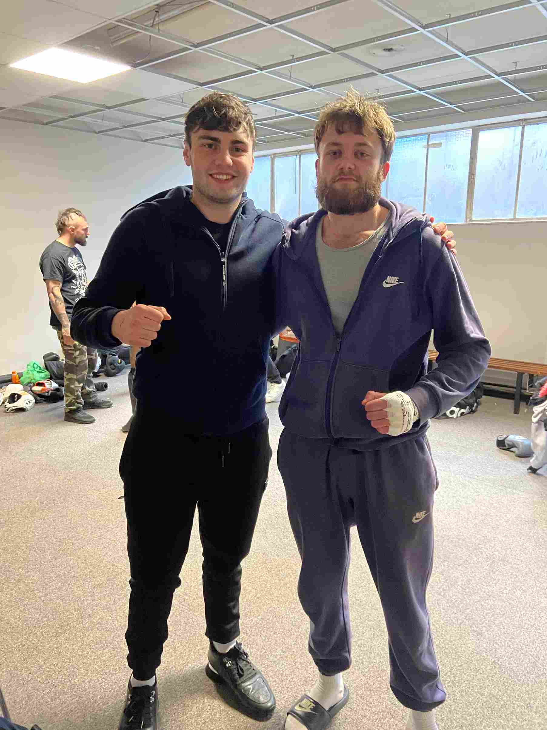 A picture of oliver taylor and a friend. They are in the changing rooms of a fight show, Oliver has his hands wrapped.