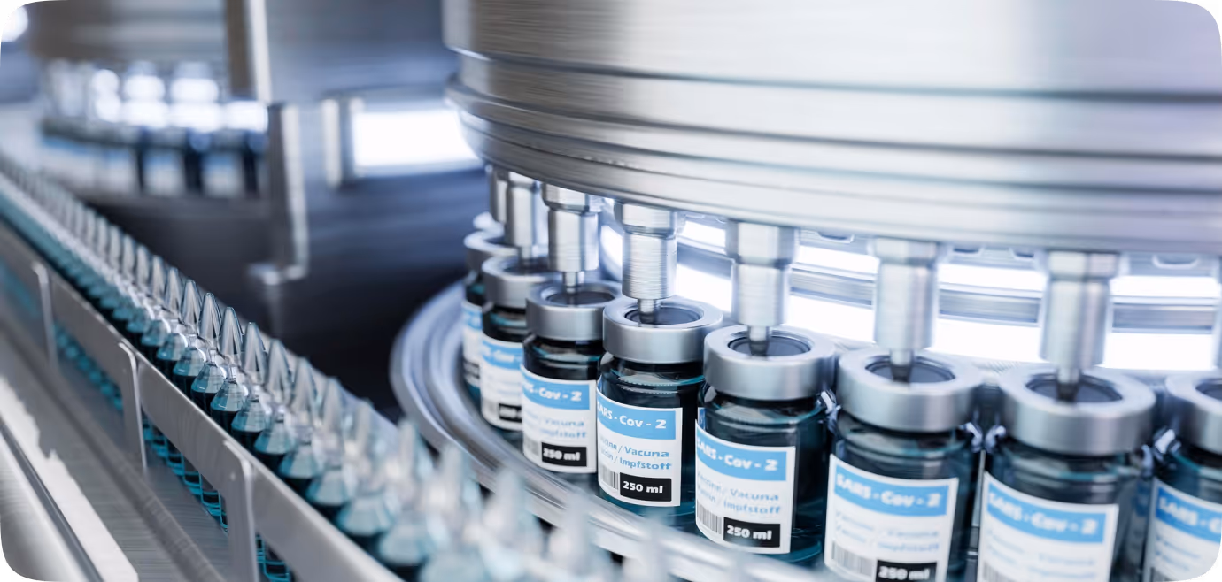 Production line with bottles labeled 'MRS-Cov-2' being filled with liquid vaccine in a pharmaceutical manufacturing setting.