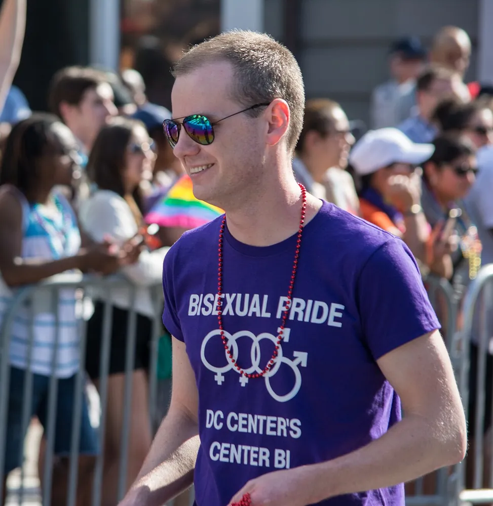 A marcher carrying a large bisexual pride flag in the Capital Pride parade, Washington, D.C., 2014