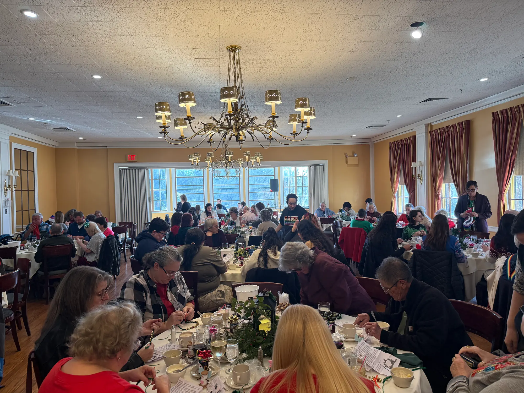 A full room of guests at round tables under a brass chandelier at last year's Intergenerational Brunch