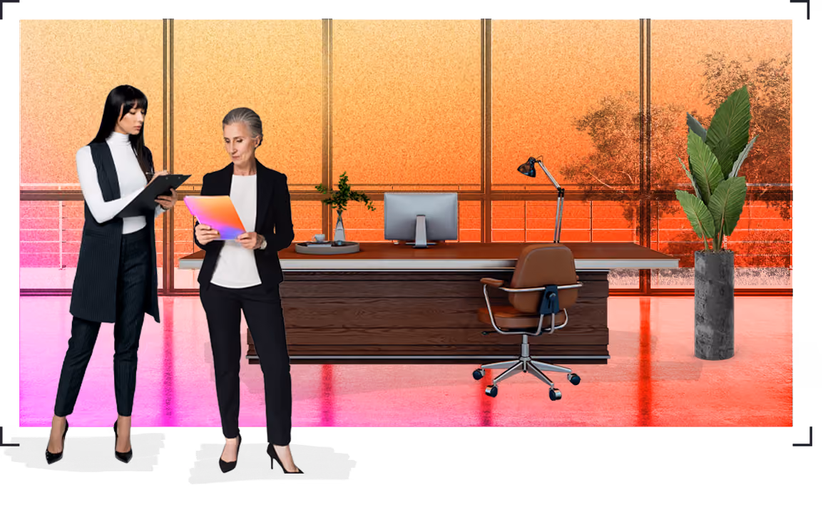 Two women in office attire reviewing documents in a modern office with large windows and a desk.