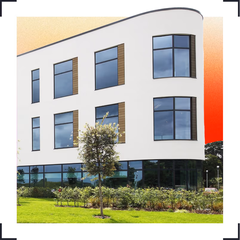 Moneypenny HQ with large windows and landscaping with trees and shrubs outside.
