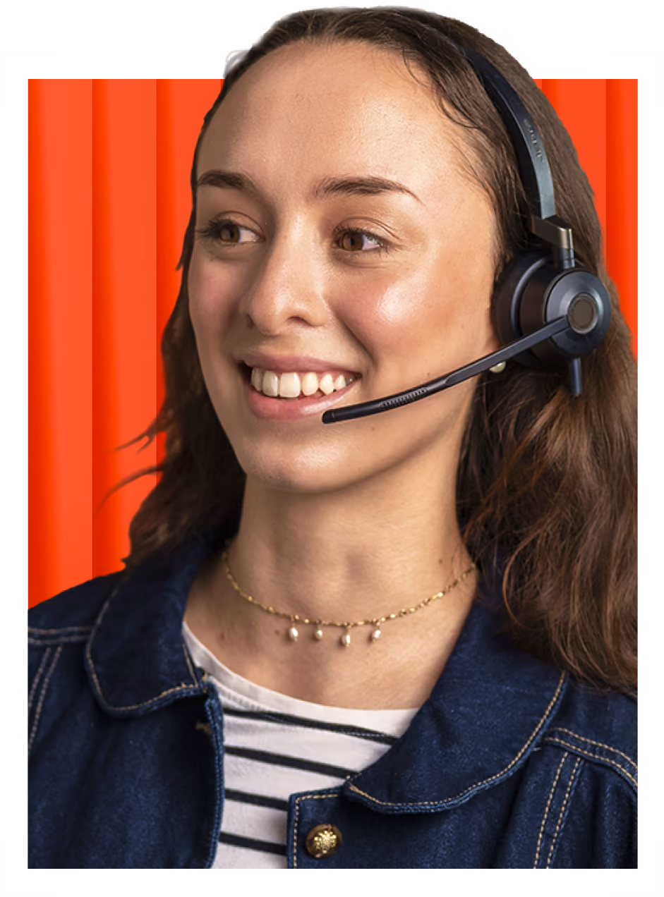 Smiling woman wearing a headset with microphone, denim jacket, and striped shirt against red background.