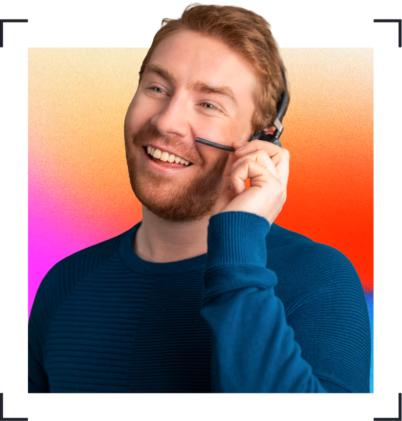 Smiling man with short hair wearing blue sweater and headset, holding microphone near mouth.
