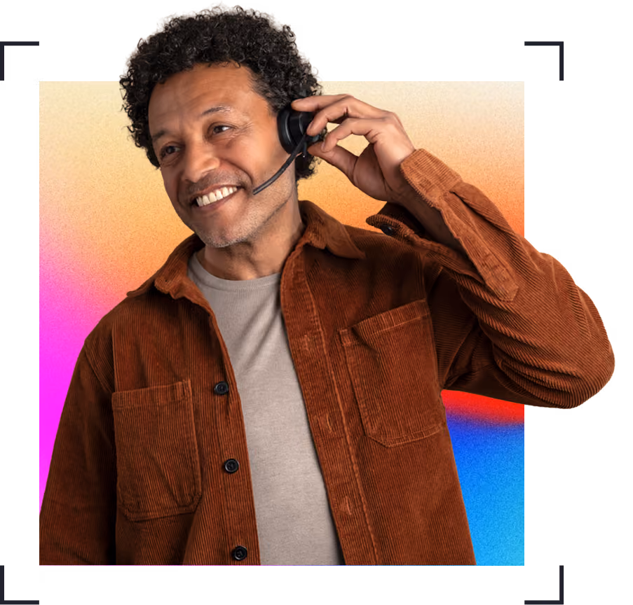 Smiling man wearing a brown corduroy shirt adjusting a headset against a gradient orange, pink, and blue background.
