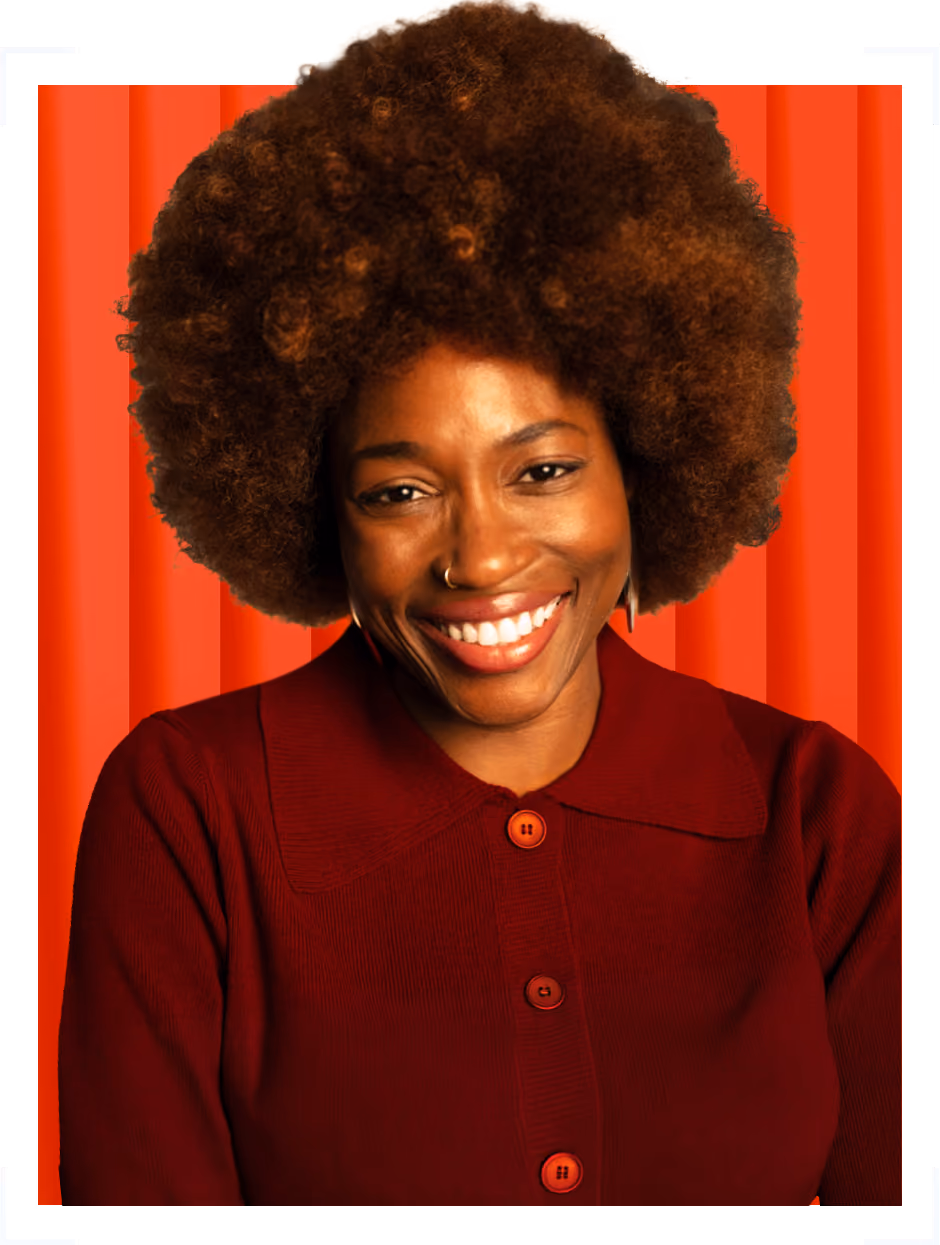 Smiling woman with large curly hair wearing a burgundy buttoned top against a red background.