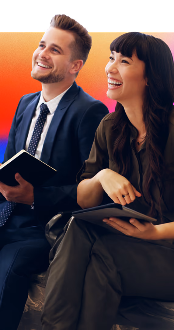 Smiling man in suit and woman with tablet laughing together against gradient background.