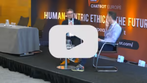Two speakers on stage discussing AI and human-centric innovation at the Chatbot Europe conference.