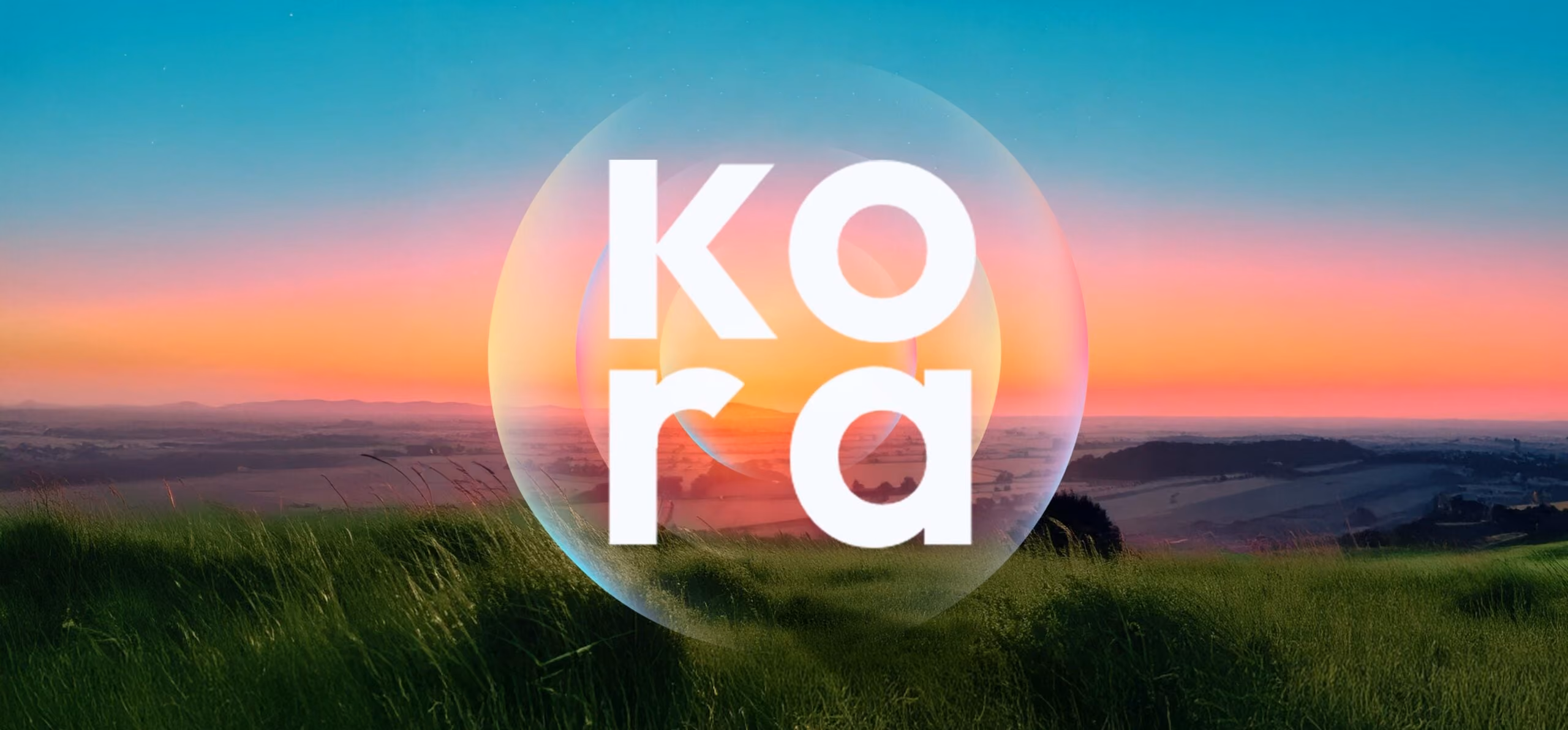 Green grassy field with distant hills at sunset in the background and the word Kora in a translucent sphere.