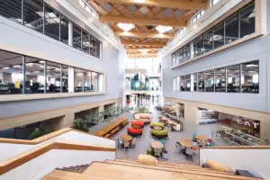 Modern, spacious office lobby with seating, wooden ceiling, and a café area labeled EAT.