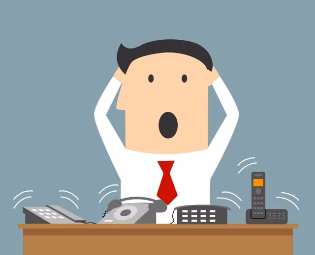 Cartoon man clutching his head at a desk with four ringing telephones around him.