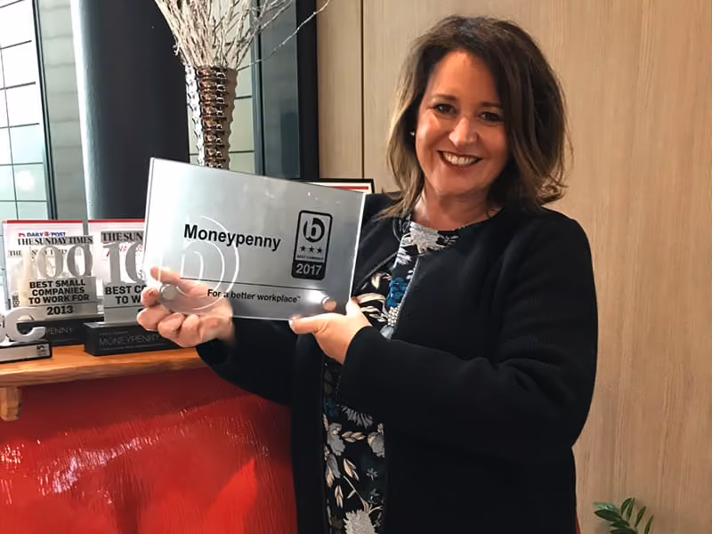 Smiling woman holding a Moneypenny 2017 best workplace award plaque indoors.