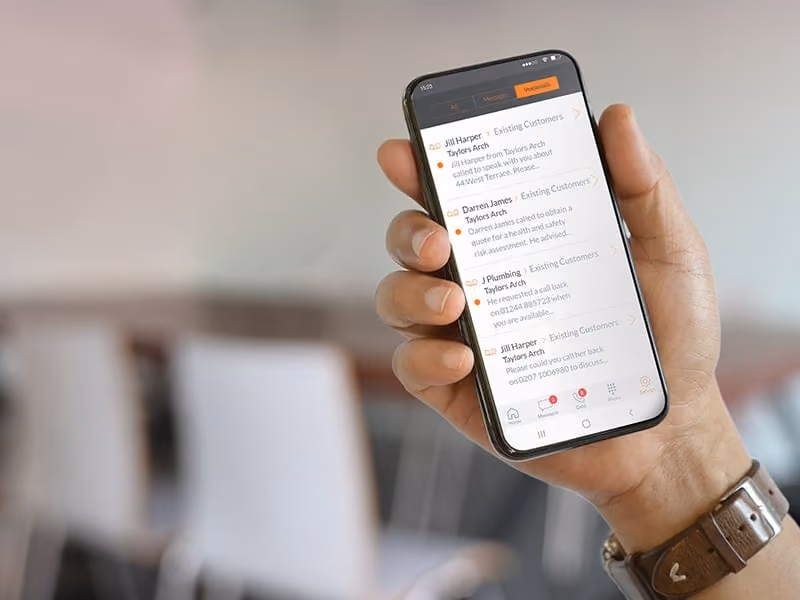Hand holding smartphone showing a voicemail app with multiple messages from customers.