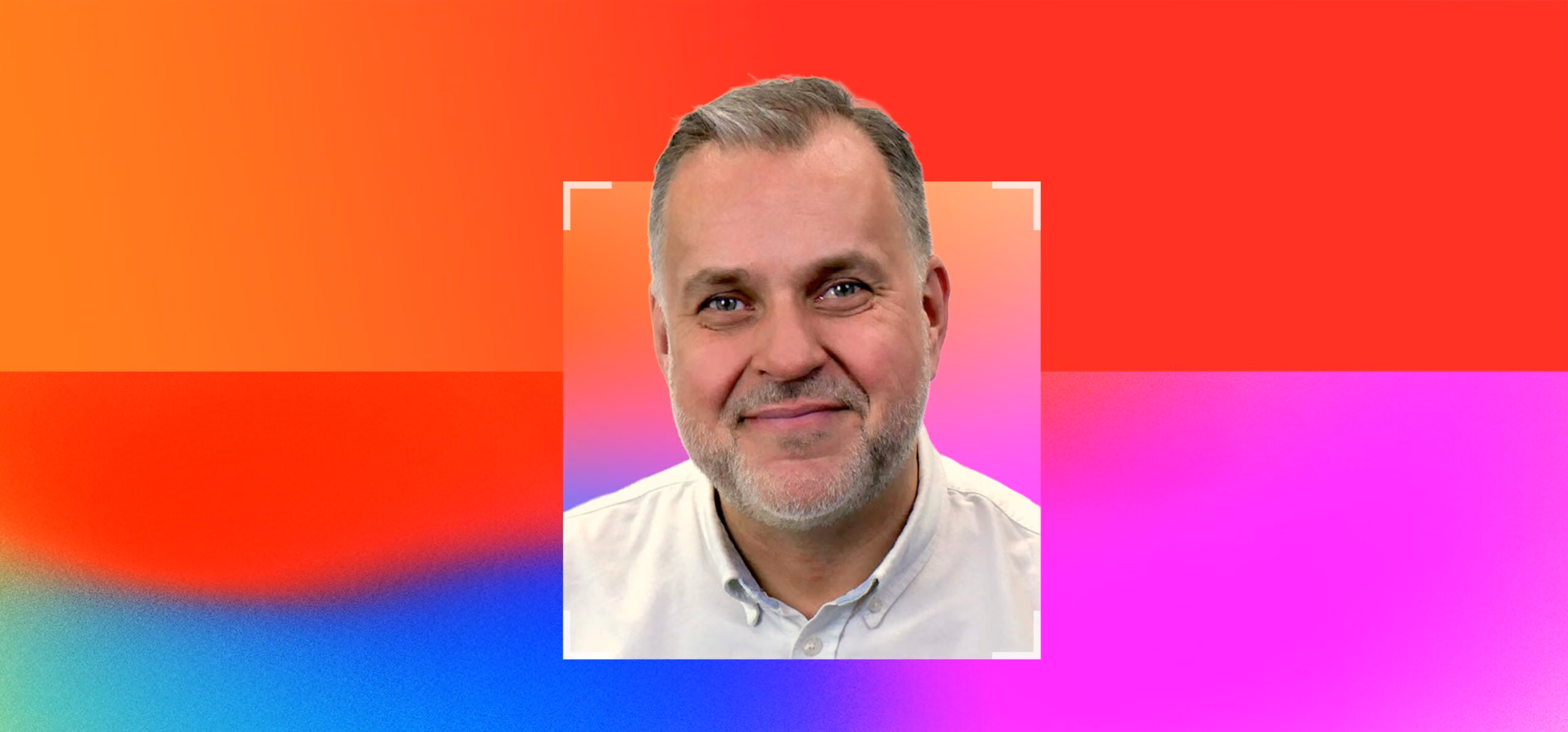 Smiling middle-aged man with gray hair and beard wearing a light shirt on a colorful gradient background.