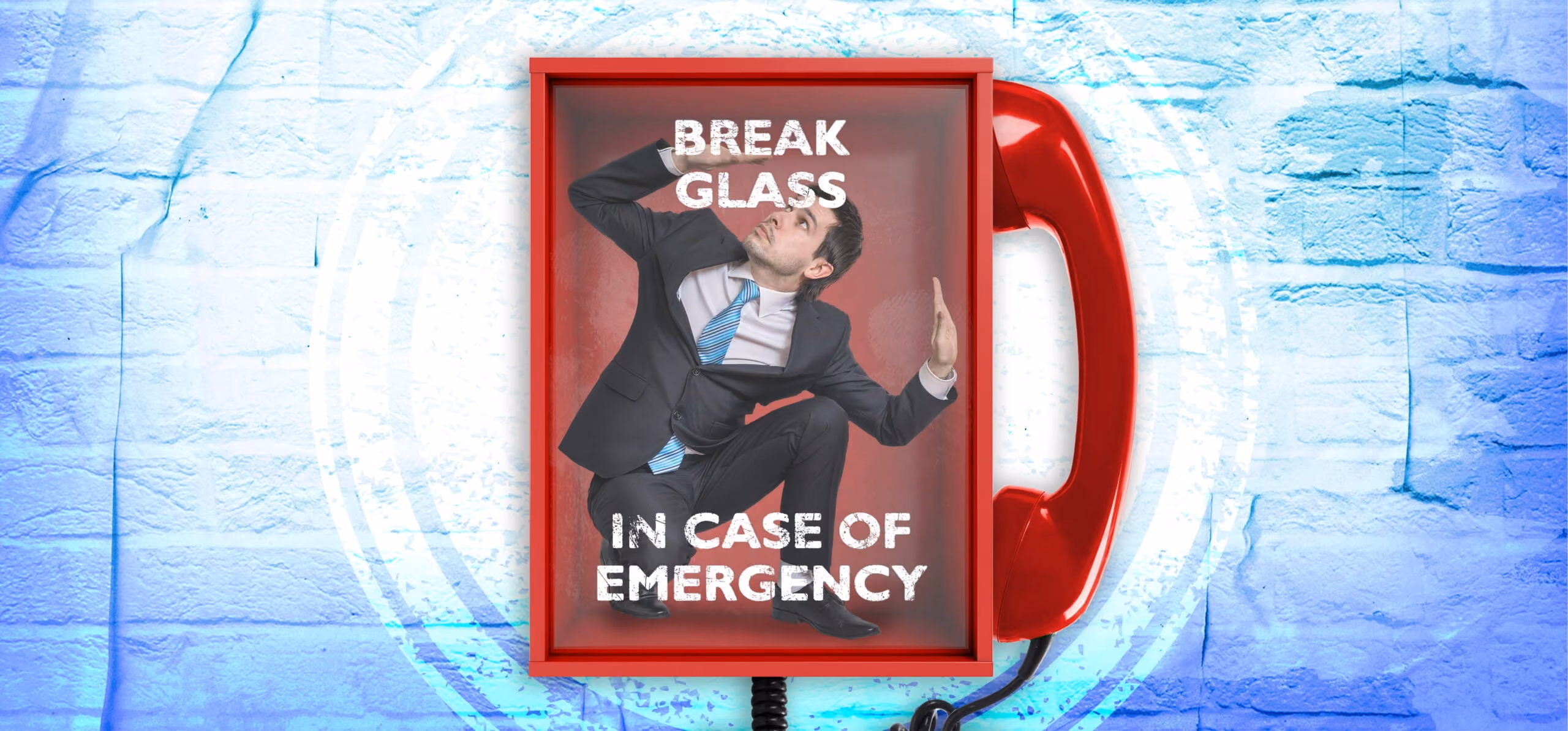 Man in a business suit trapped inside a phone booth with emergency break glass sign.
