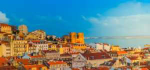 View of Lisbon’s Alfama district with colourful rooftops and historic buildings overlooking the Tagus River.