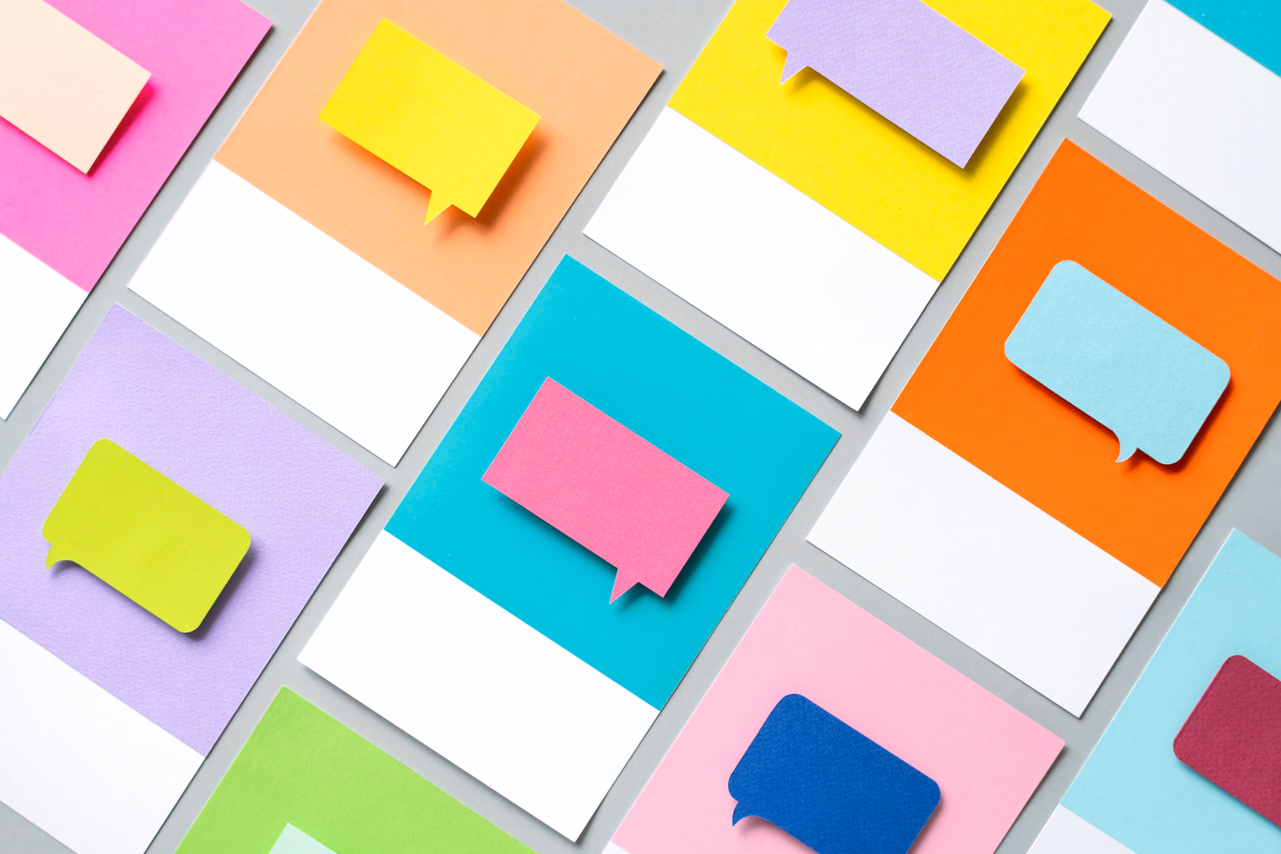 Colorful paper cards with matching speech bubble cutouts arranged diagonally on a gray background.