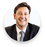 Portrait of a smiling man in a suit and tie against a white background.