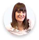 Smiling woman with brown hair and bangs wearing a white shirt against a white background.