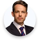 Professional headshot of a man in a suit and striped tie against a plain white background.