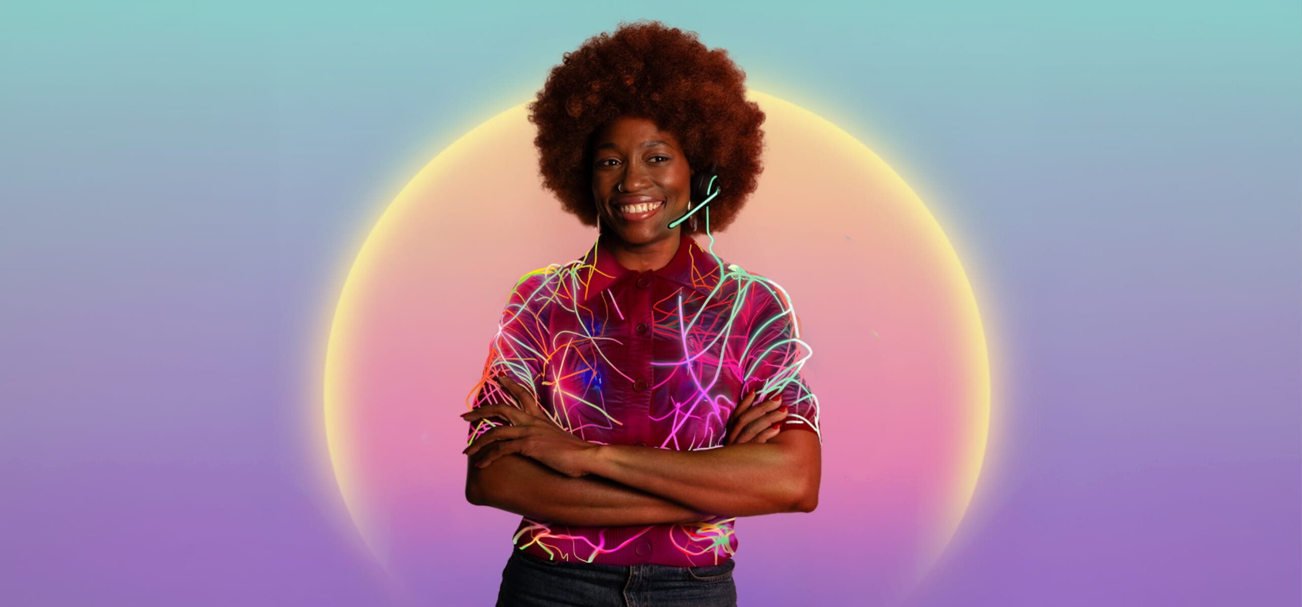 Smiling woman with an afro hairstyle and a headset, wearing a short-sleeved red shirt with colorful neon light patterns, stands with arms crossed against a purple and teal gradient background with a glowing yellow circle behind her.