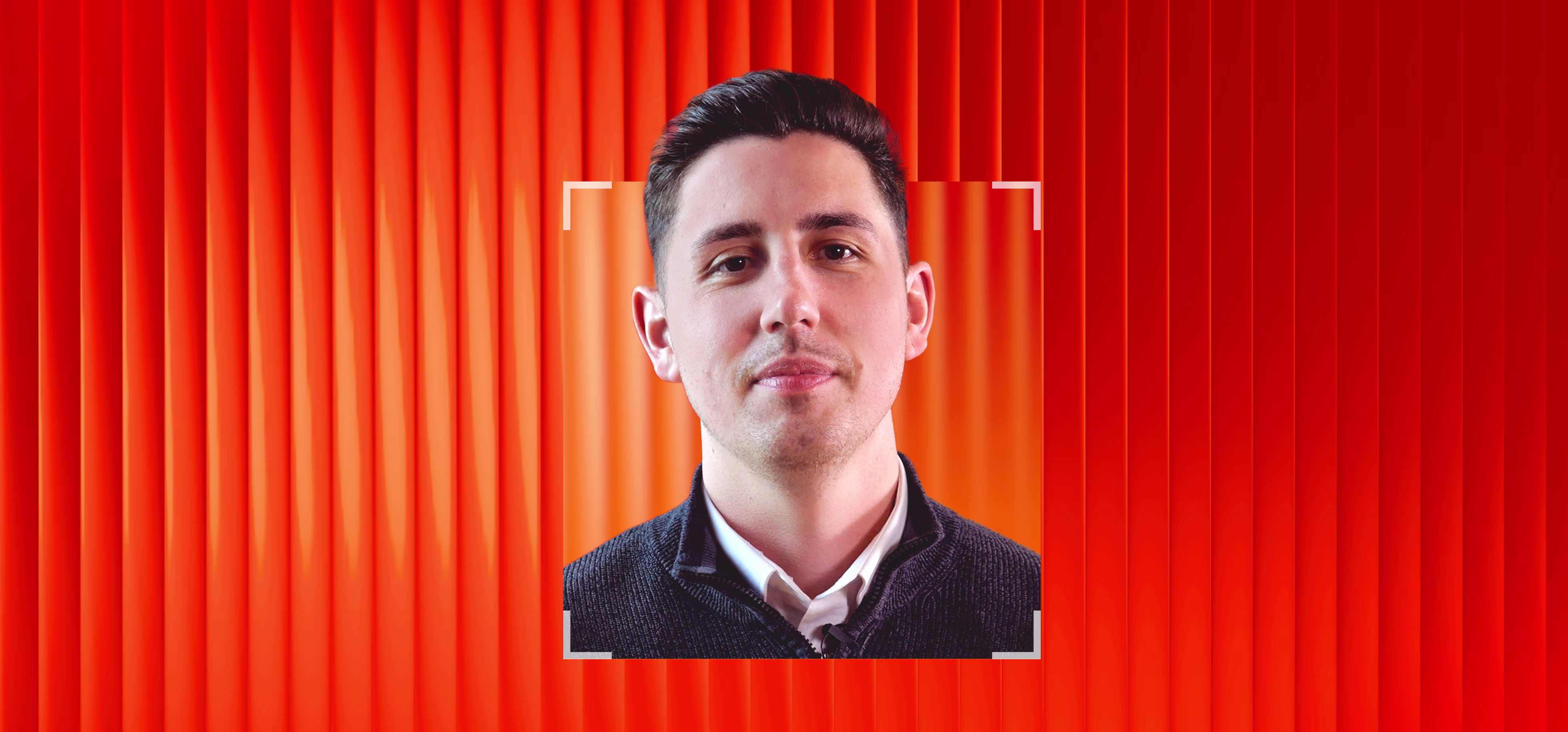 A young man with short dark hair and a slight smile is framed by a square white focus box against a background of vertical orange-red gradients.