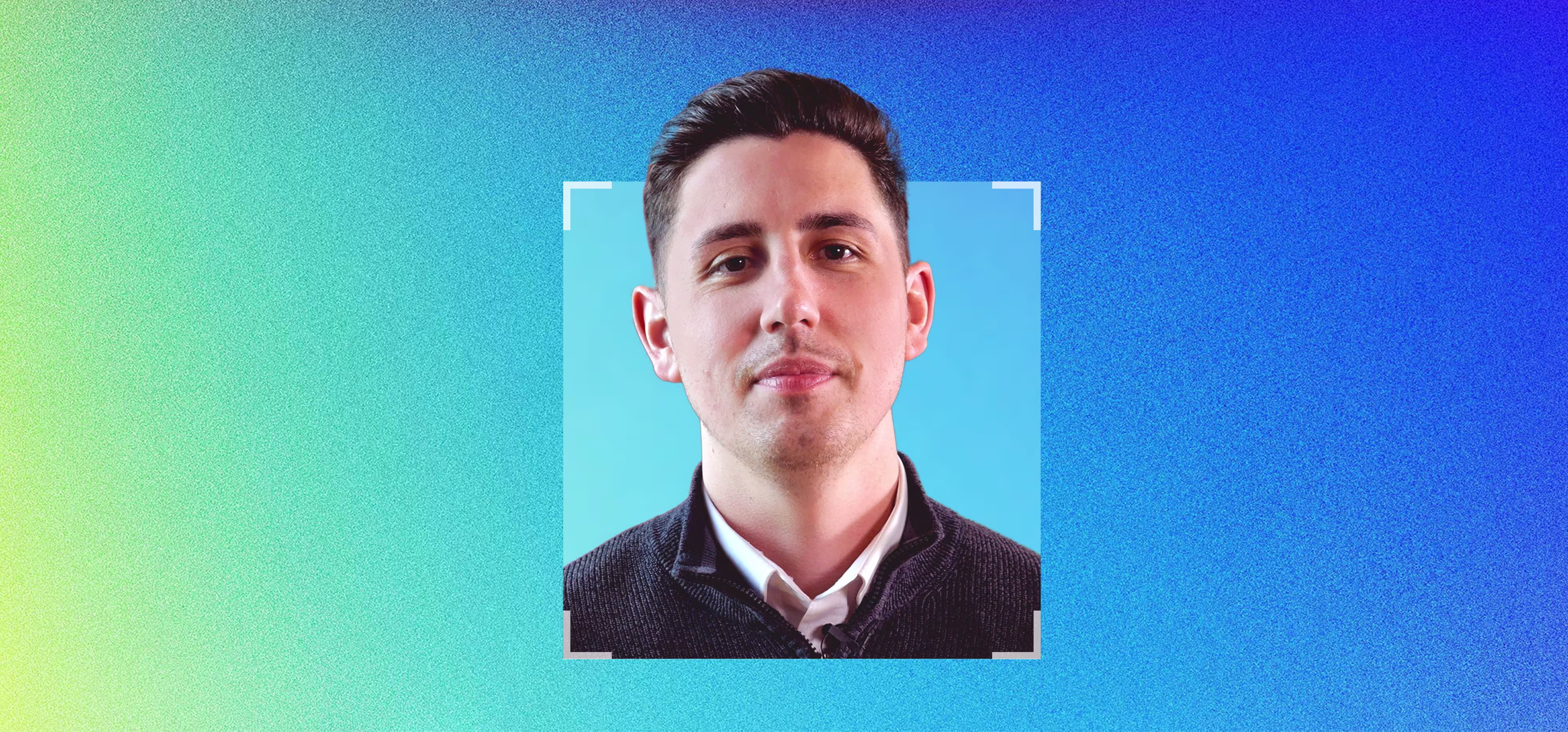 Portrait of a young man with short dark hair and a light stubble, wearing a white shirt and a dark sweater, against a blue and gradient background with a square framing around his face.