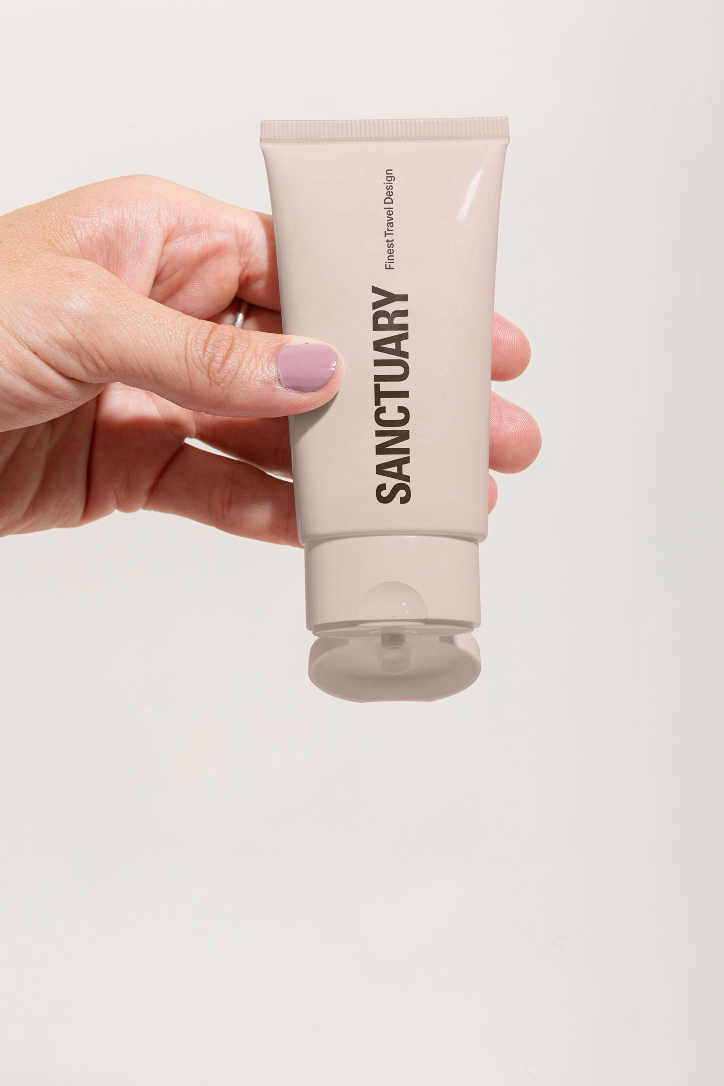 Hand holding a pale tube with a black Sanctuary wordmark