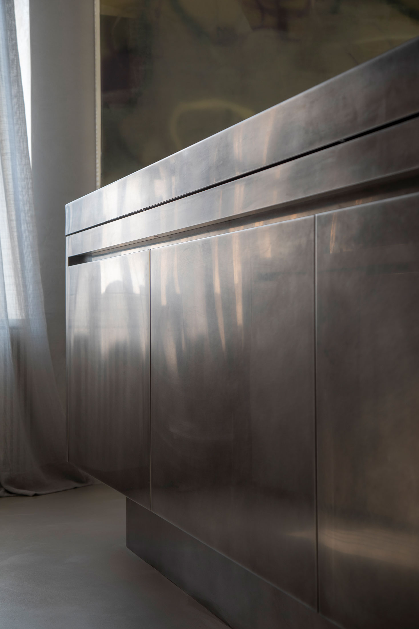 Reflected light on dark built-in cabinetry beside a curtain