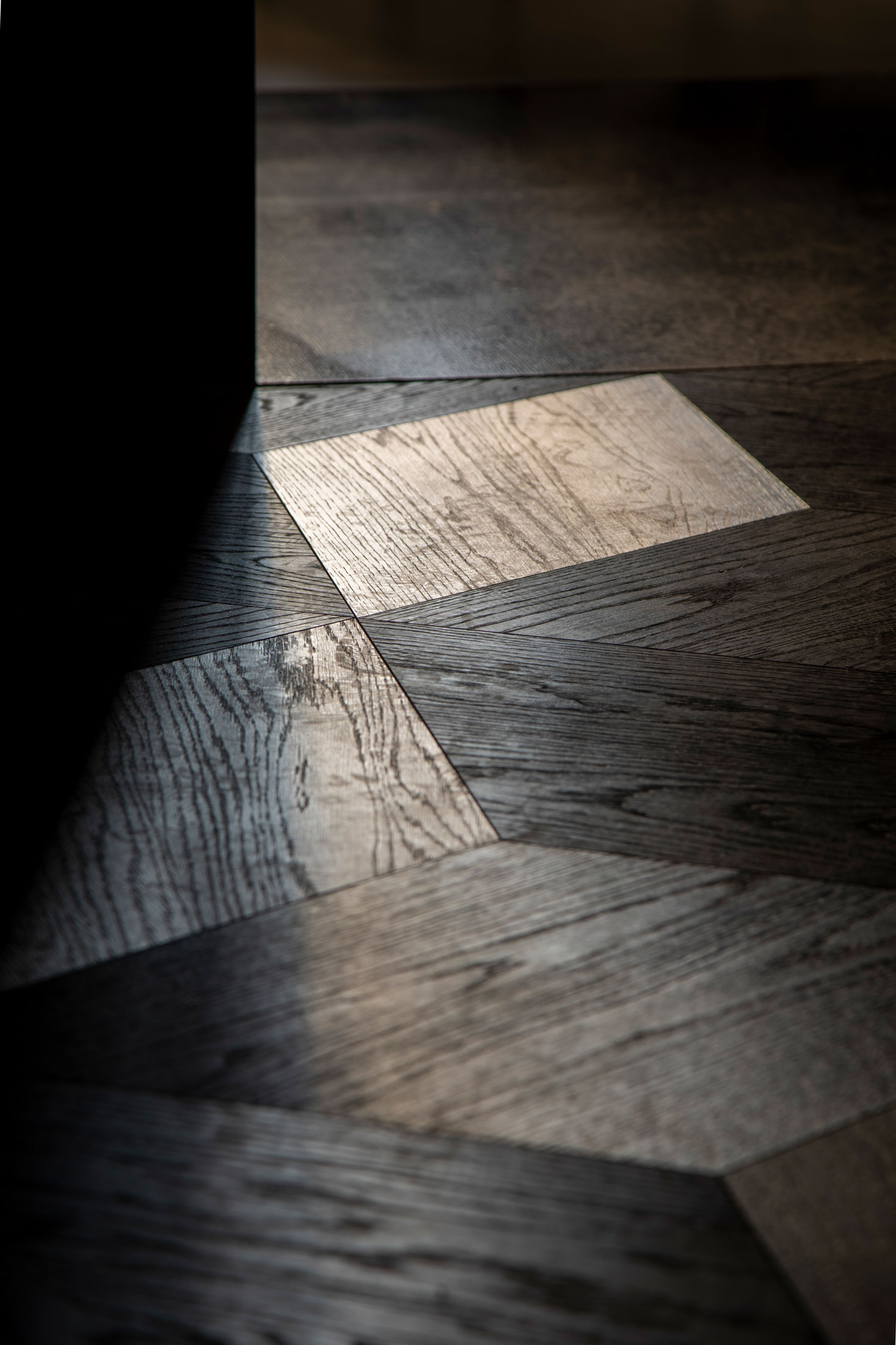 Rectangular patch of sunlight on dark parquet flooring