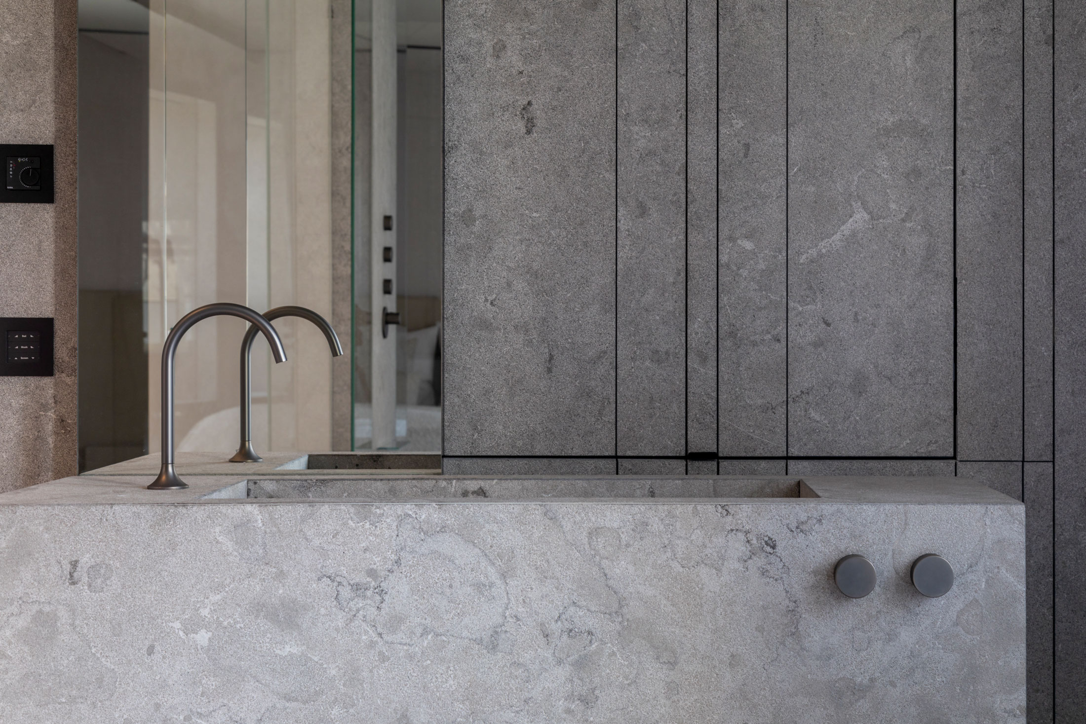 Large stone basin in front of a wall of cabinet fronts